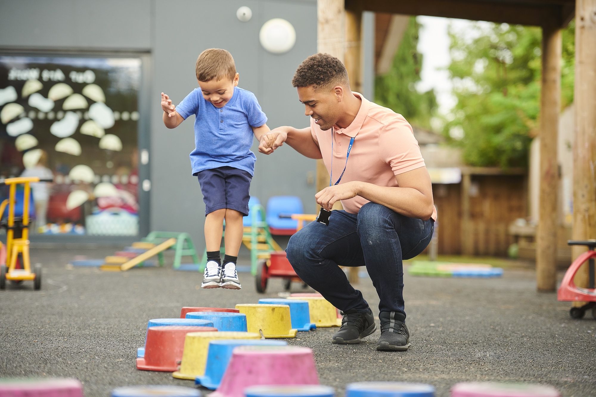 male teacher helping young student jumping comes
