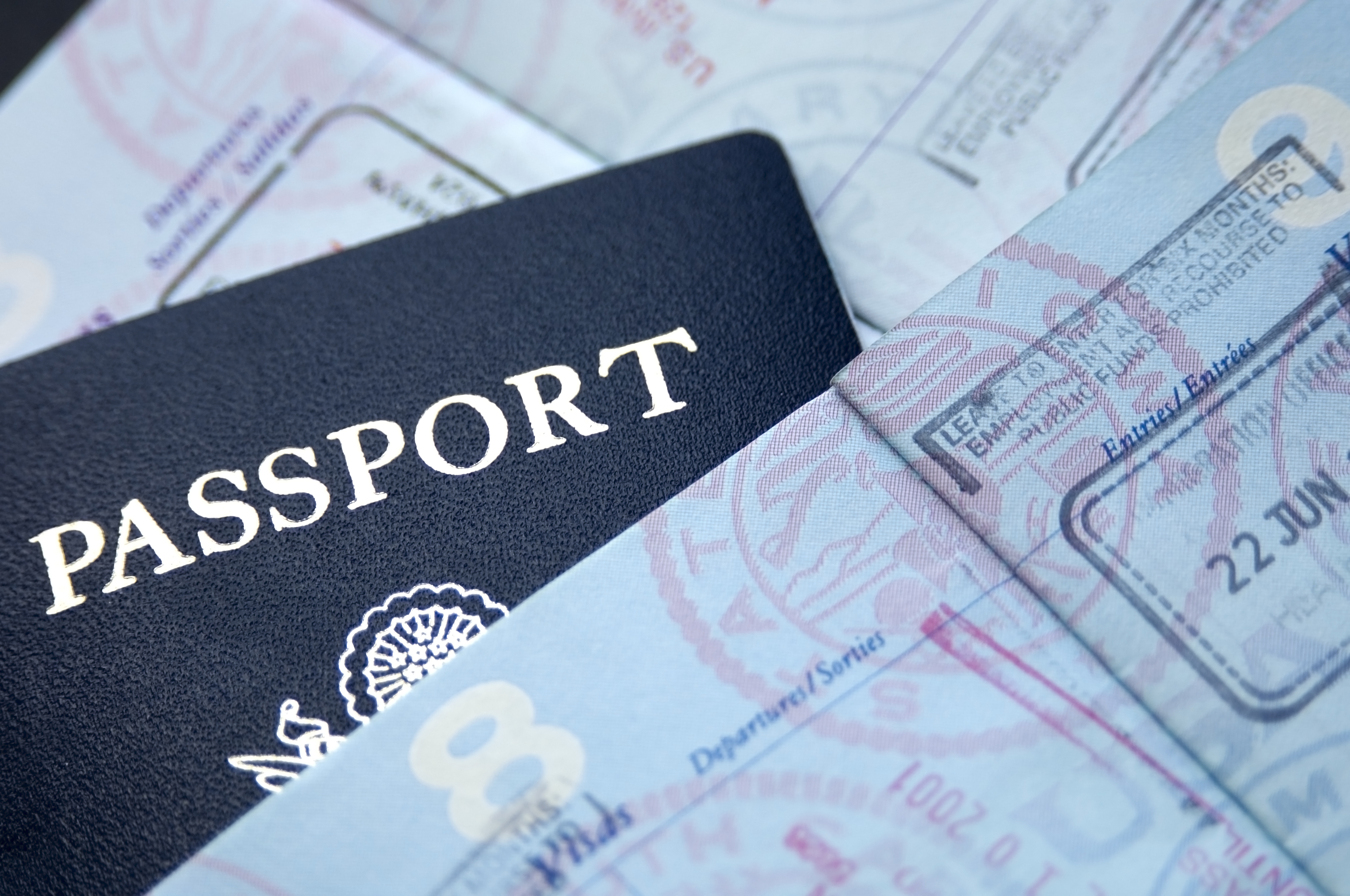Close-up of a dark blue U.S. passport partially tucked between pages filled with various international entry and exit stamps.