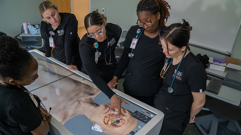 Students stand around an Anatomage Table