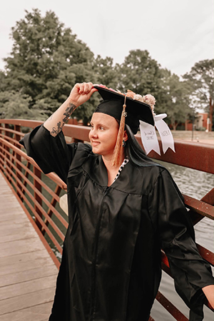 Ashtin Bullard walking across a bridge in cap and gown