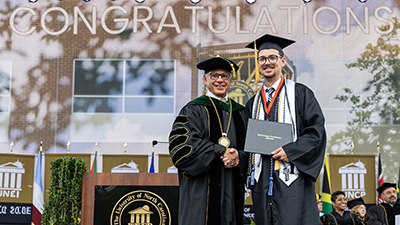 Chancellor Robin Gary Cummings presents 19-year-old Nick Smith, the youngest graduate, with his diploma during UNCP's Spring Commencement ceremony.