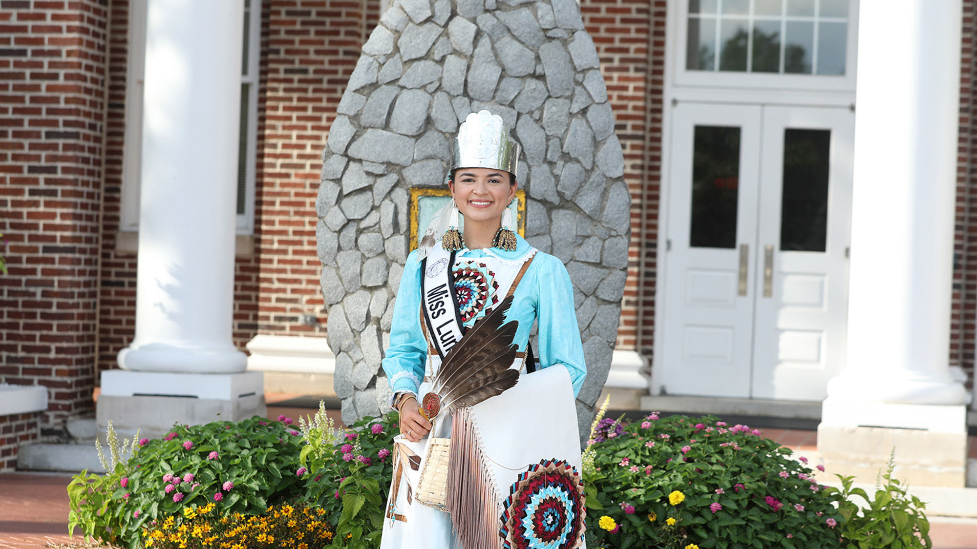Miss Lumbee, Taylor Davis, stands before the arrowhead statue in front of Old Main.