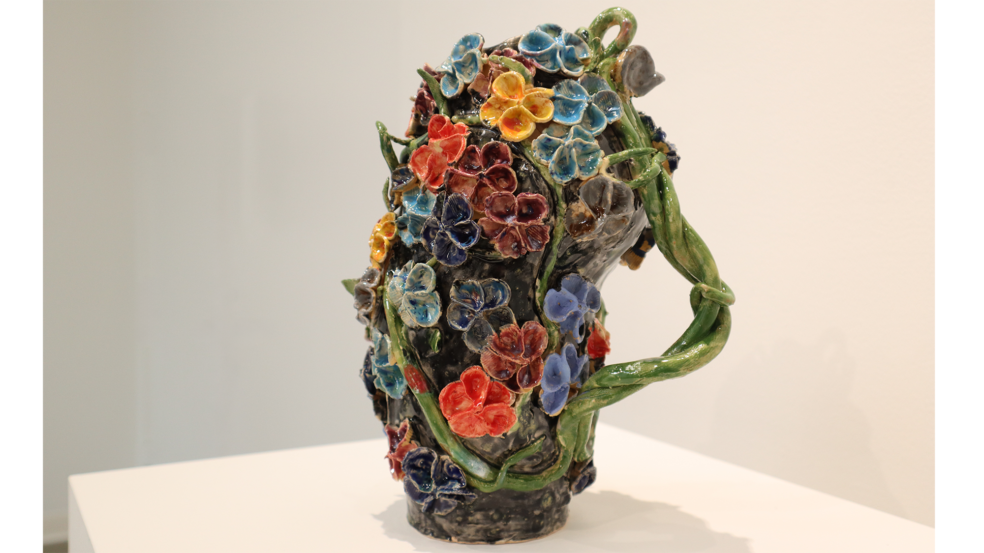 ceramic vase with extruded flowers and a vine as the handle