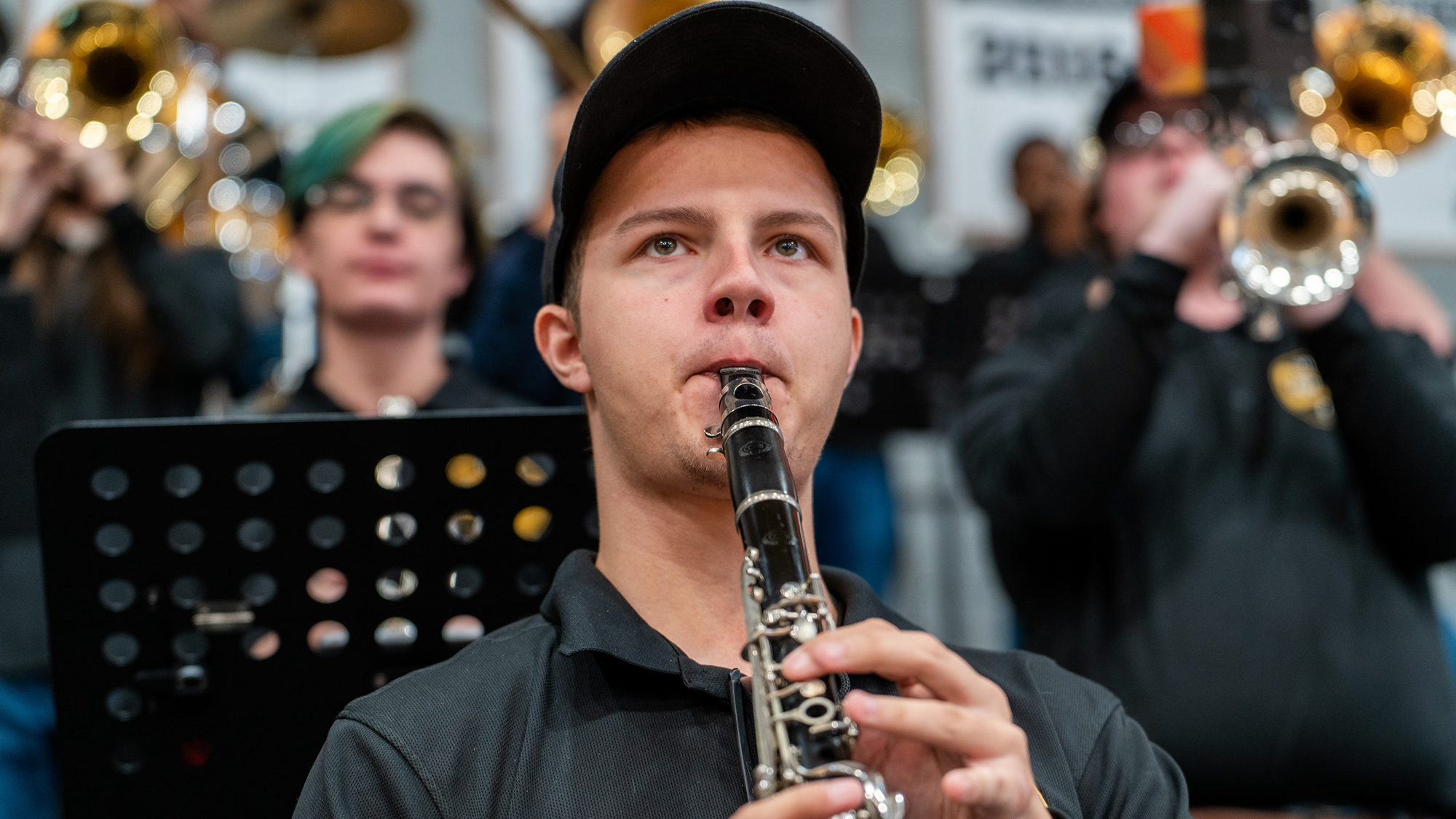 student in pep band playing a clarinet with other musicians blurred in the background