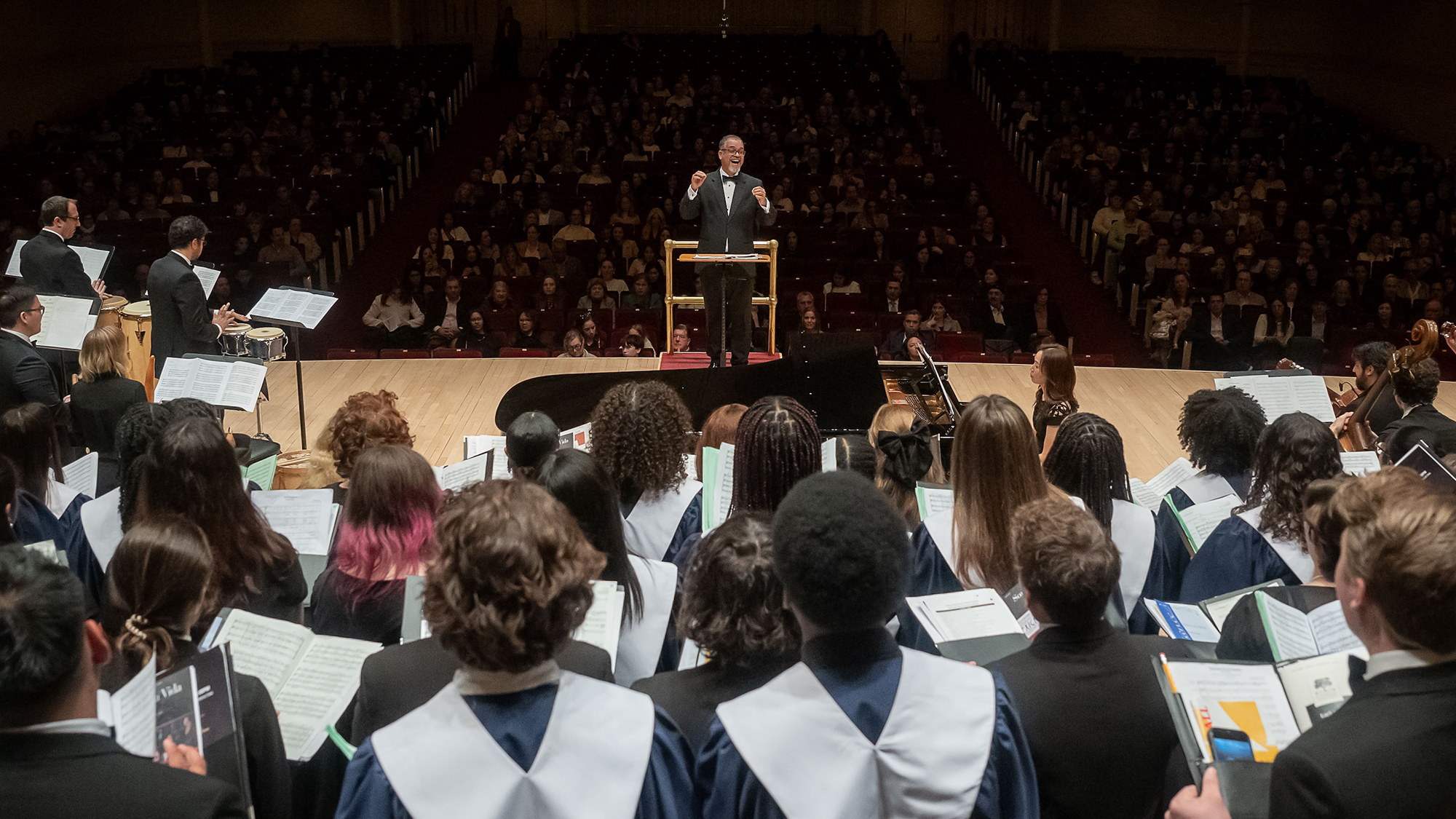 rear view of the student choir singing while conductor conducts