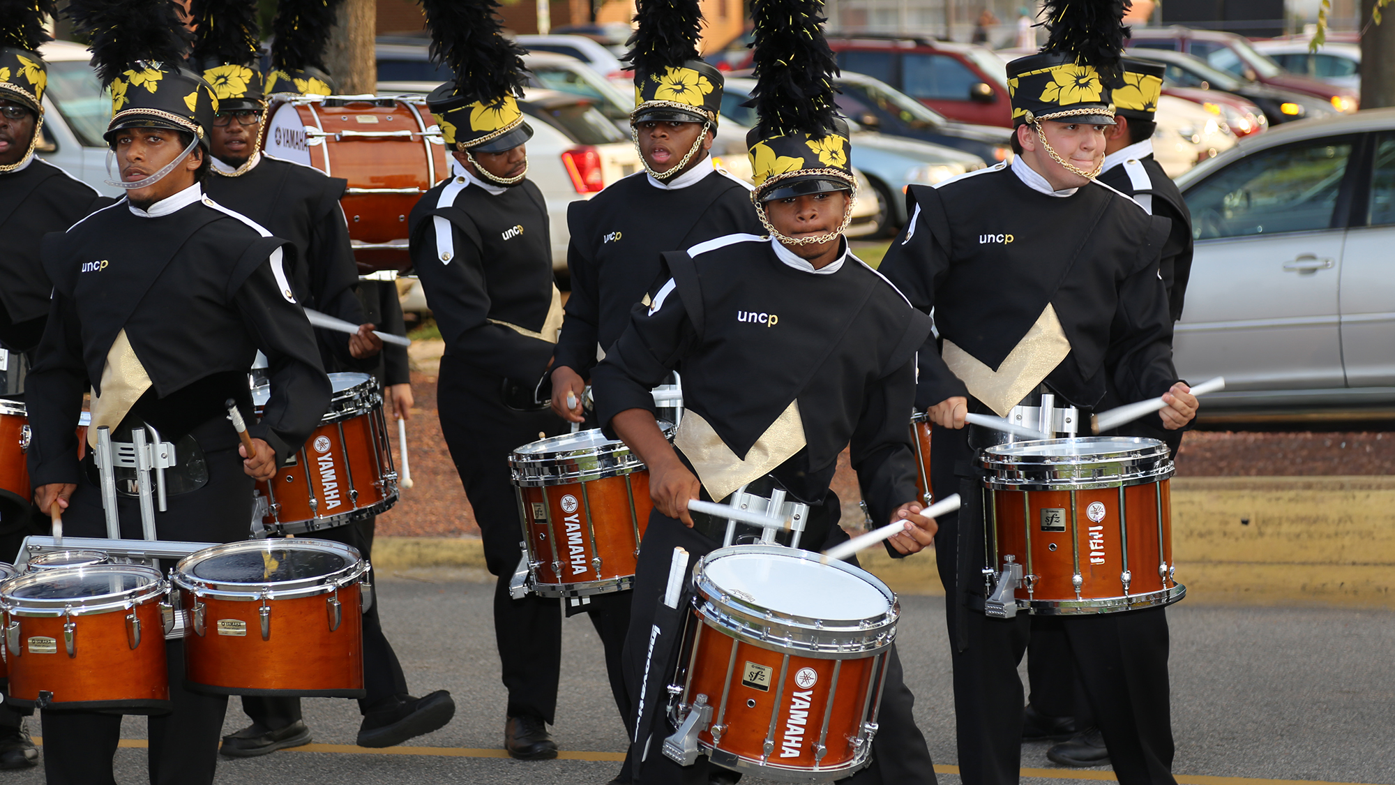 drumline playing as they march through parking area