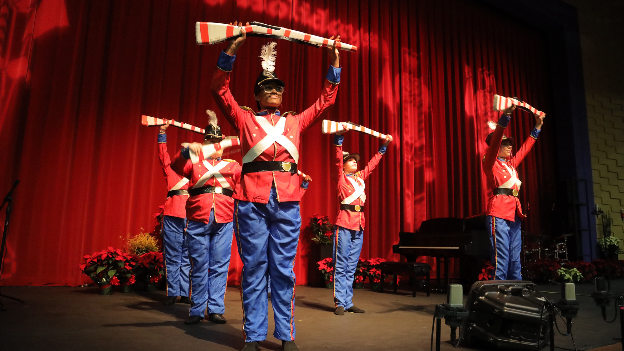 colorguard holding up rifles on stage during a performance