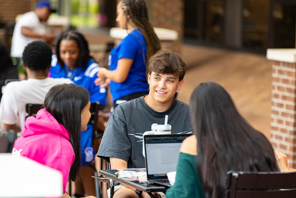 students on campus at table smiling UNCP