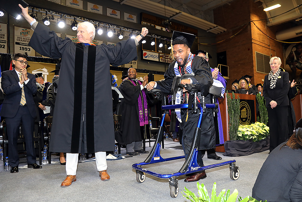 Dustin Chavis crossing stage at commencement with walker.