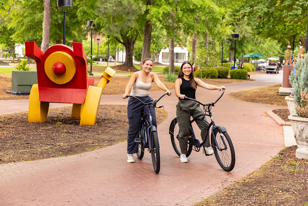 two girls on bikes UNC Pembroke campus