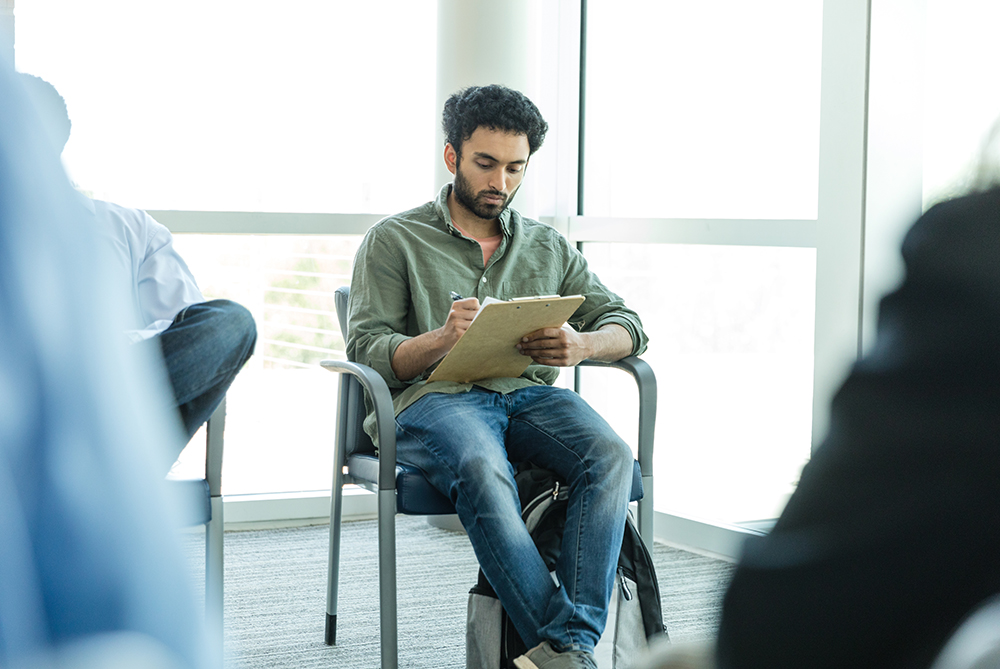 A student filling out paperwork in a doctors office lobby