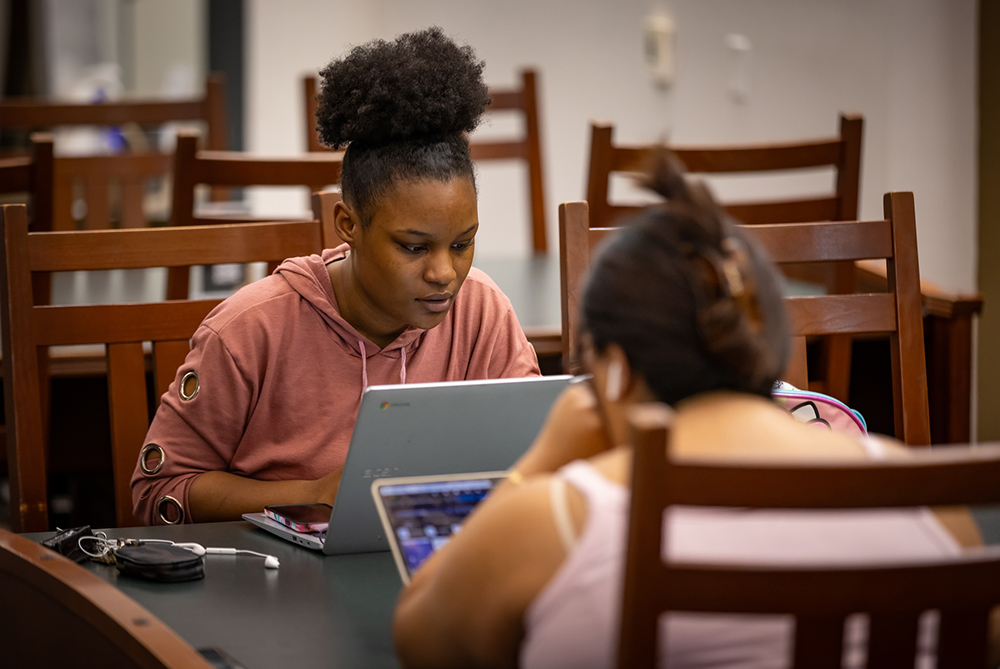 UNCP student sitting in the library on a computer