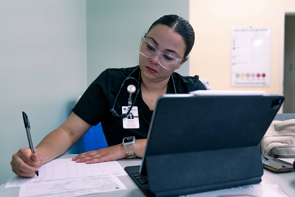 UNC Pembroke nursing student taking notes at desk