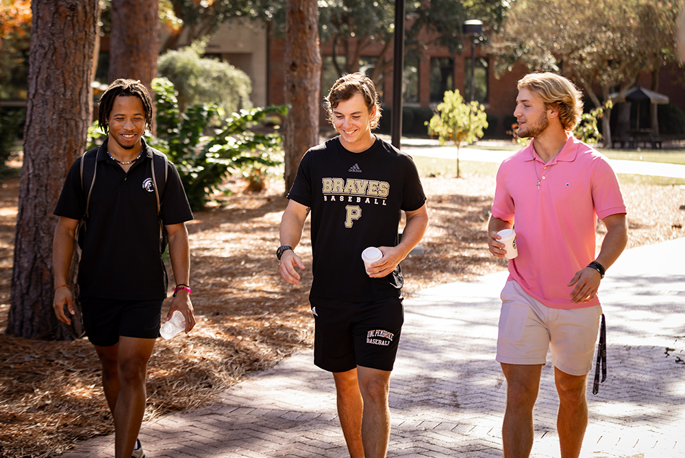 3 male students walking and talking on campus