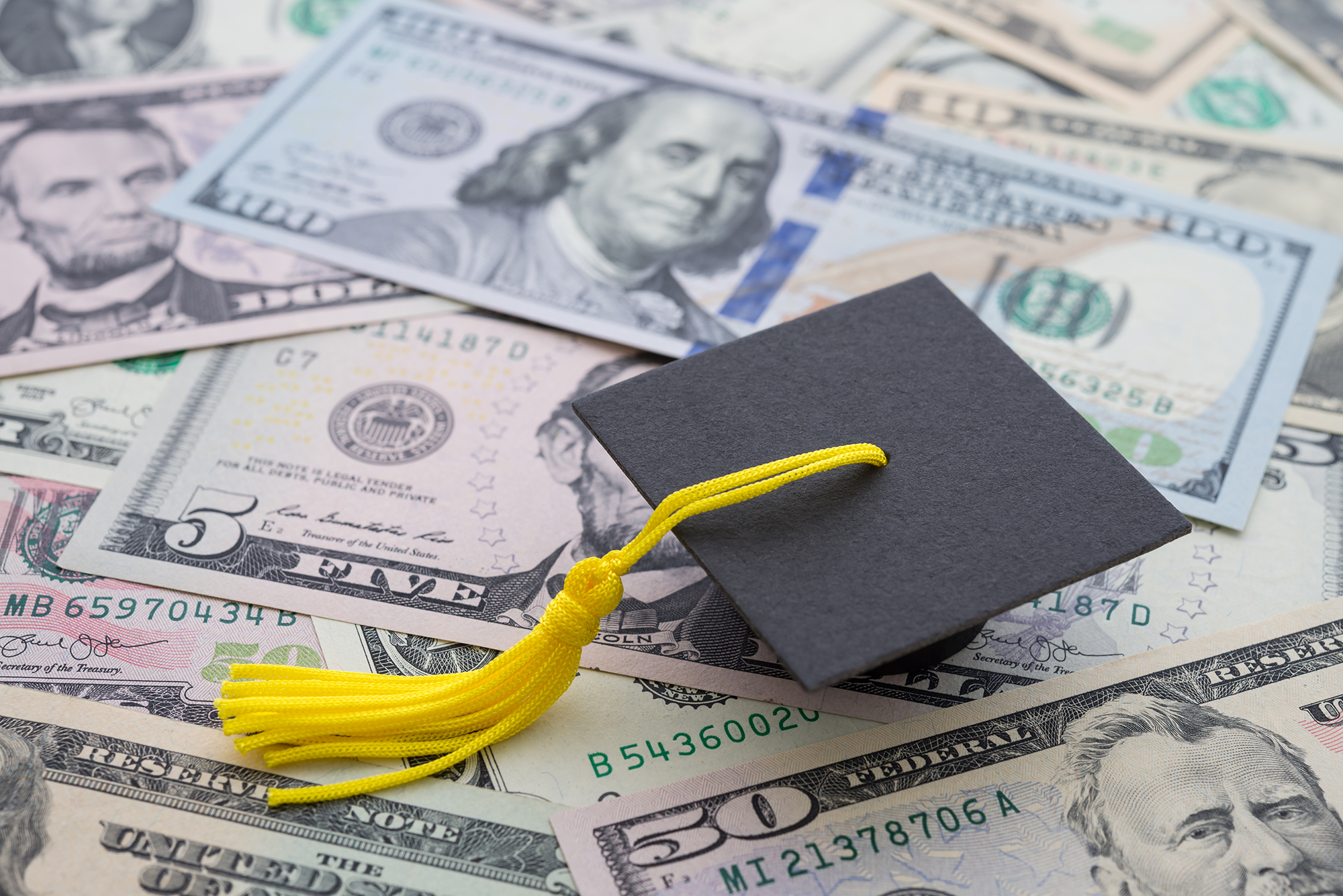 graduation cap on top of money