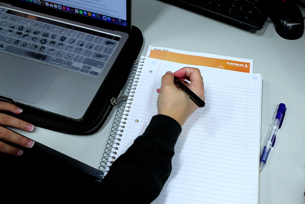 Student working with a notebook and laptop.