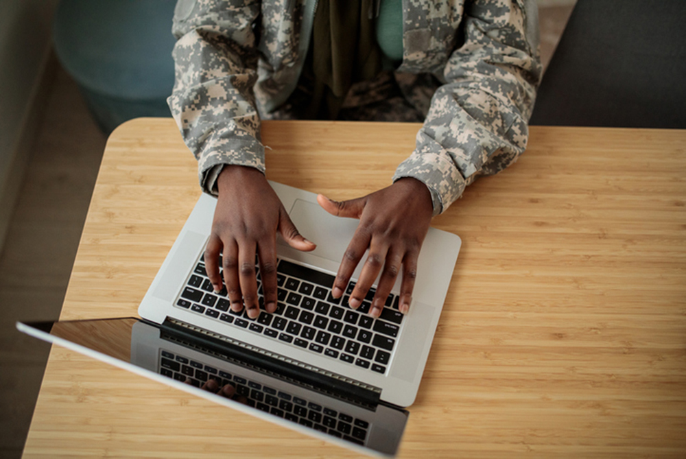 soldier's hands typing on a laptop