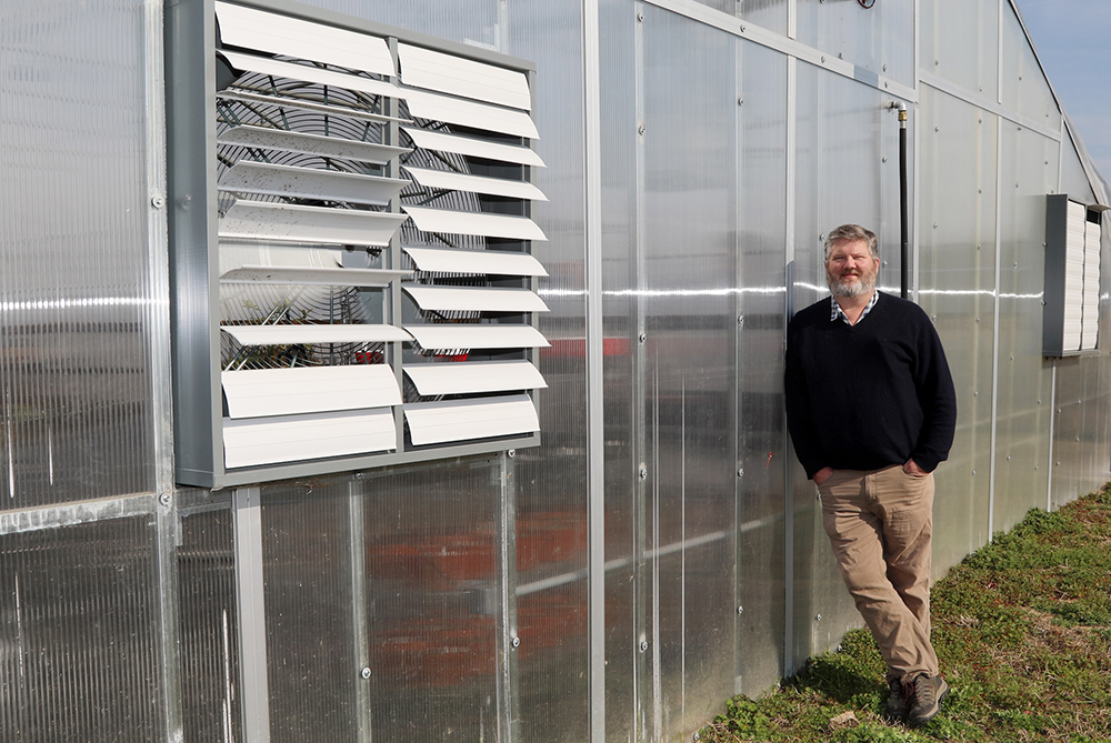 Jeff Beasley standing beside greenhouse