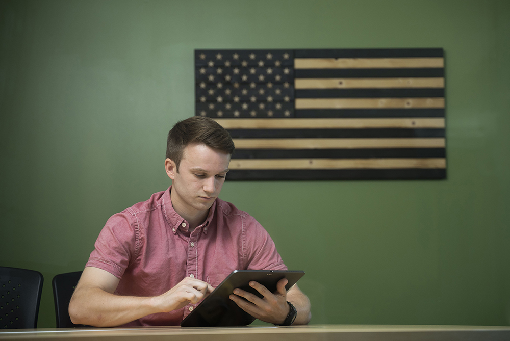 man sitting at a computer under an American flag