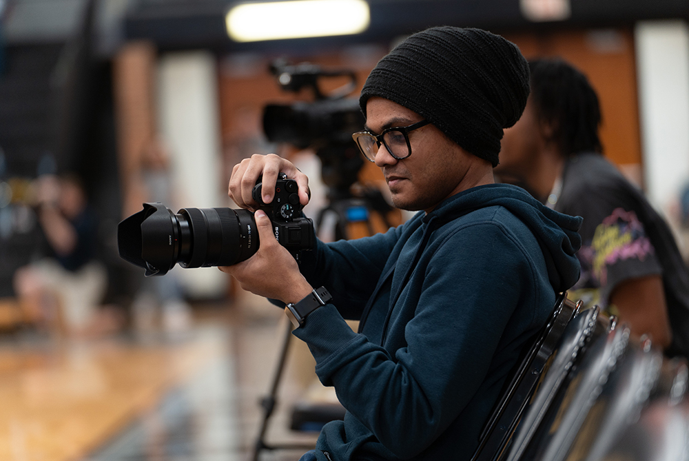 Student photographs from the sidelines of a UNCP home basketball game