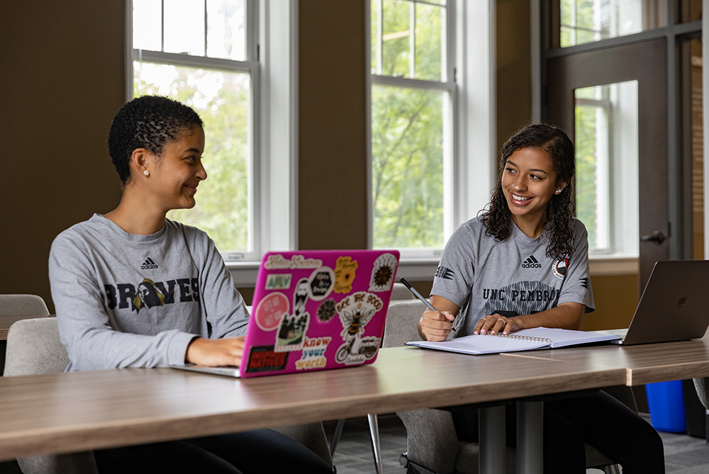 two females at table with laptop UNC Pembroke