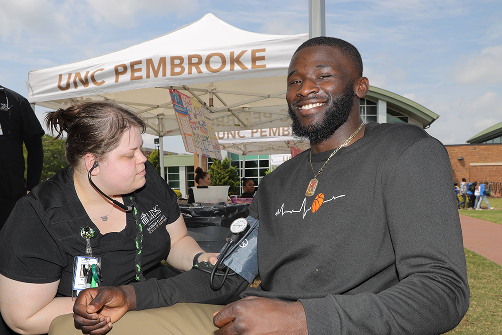 UNCP nursing student checking blood pressure at the Health and Wellness Fair