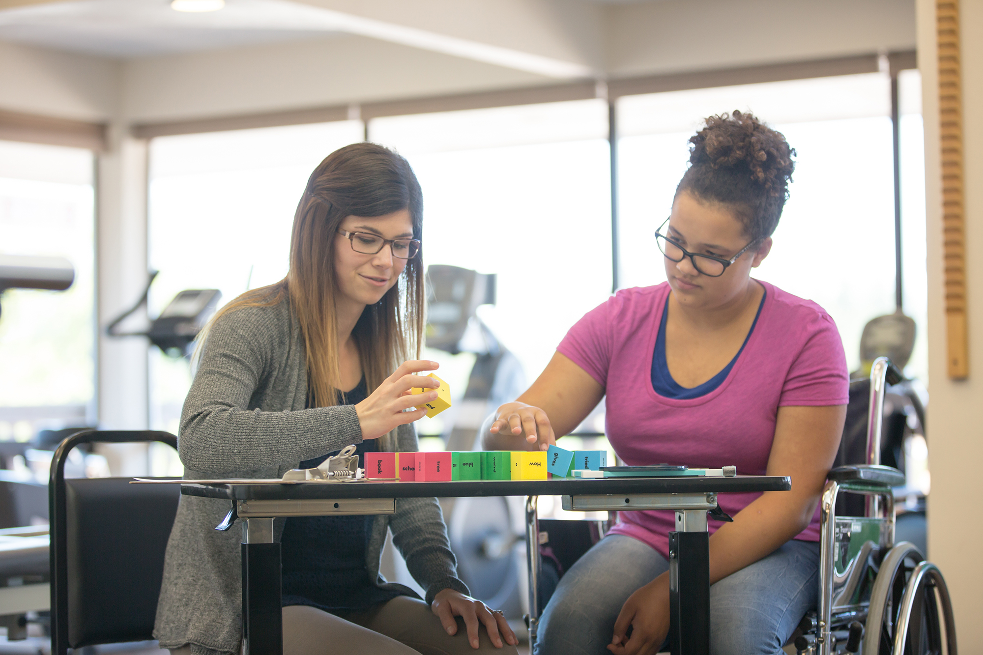 woman helps teen with blocks in occupational therapy setting