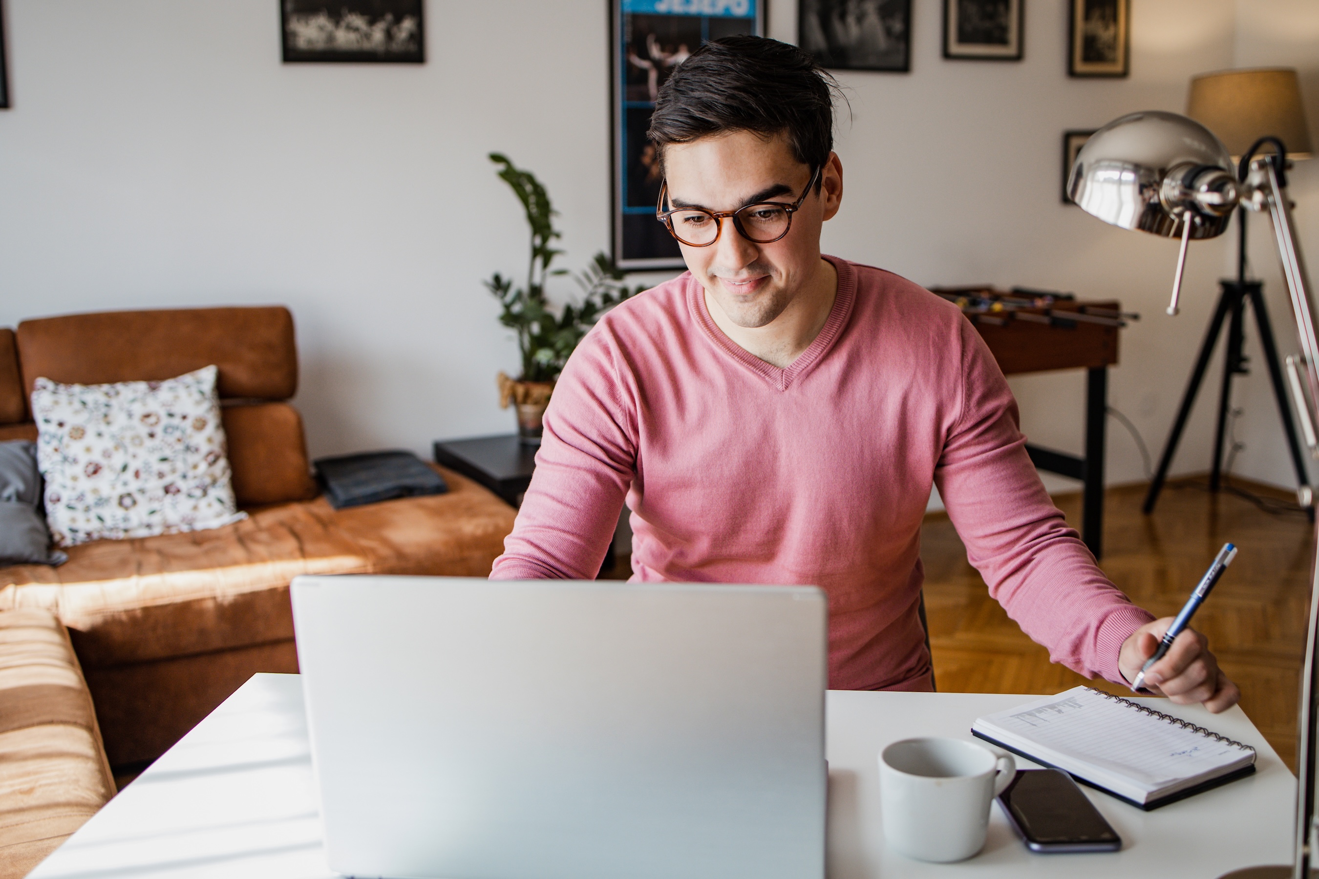 Guy at home on laptop with pen and paper