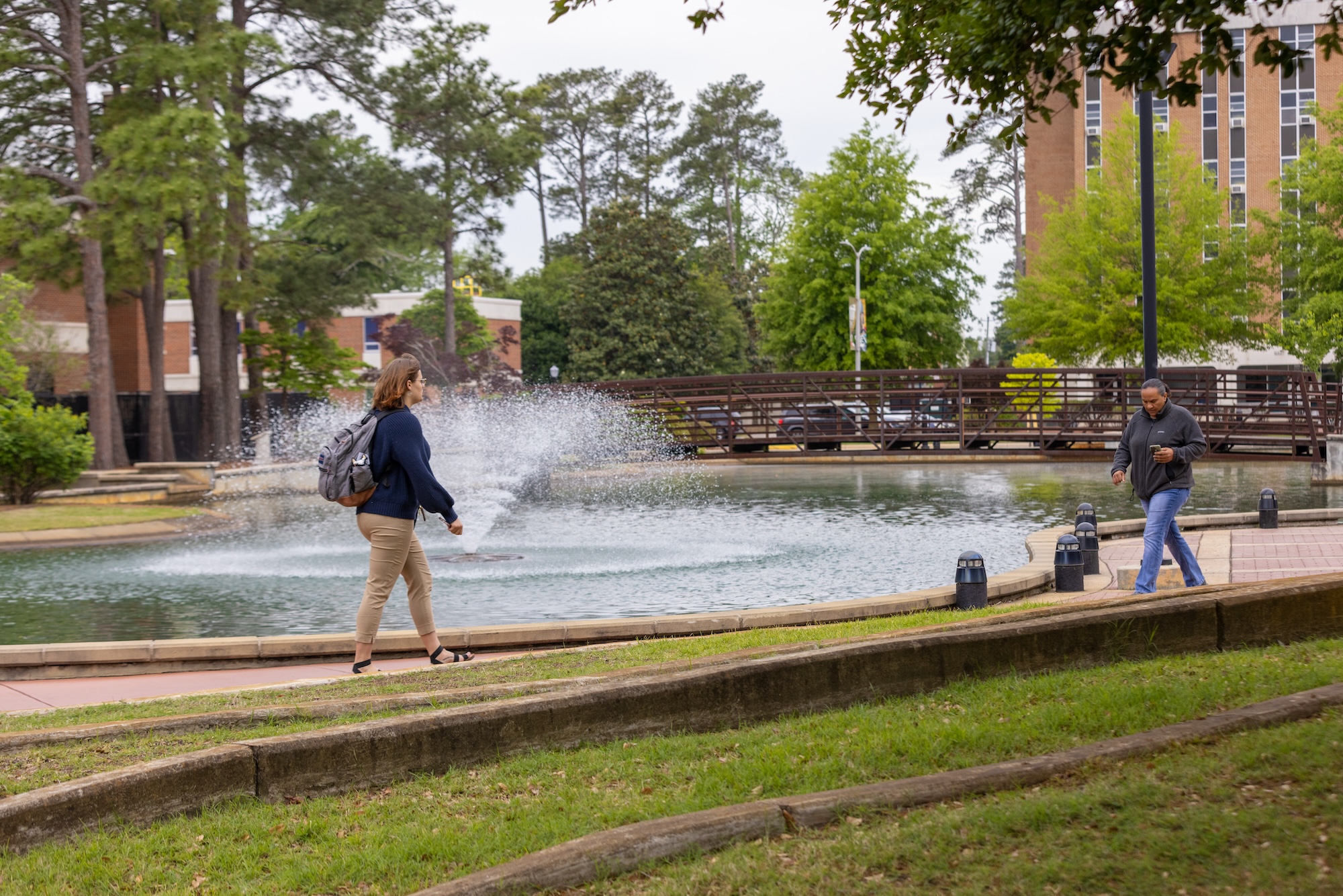 people walking on campus near the water feature