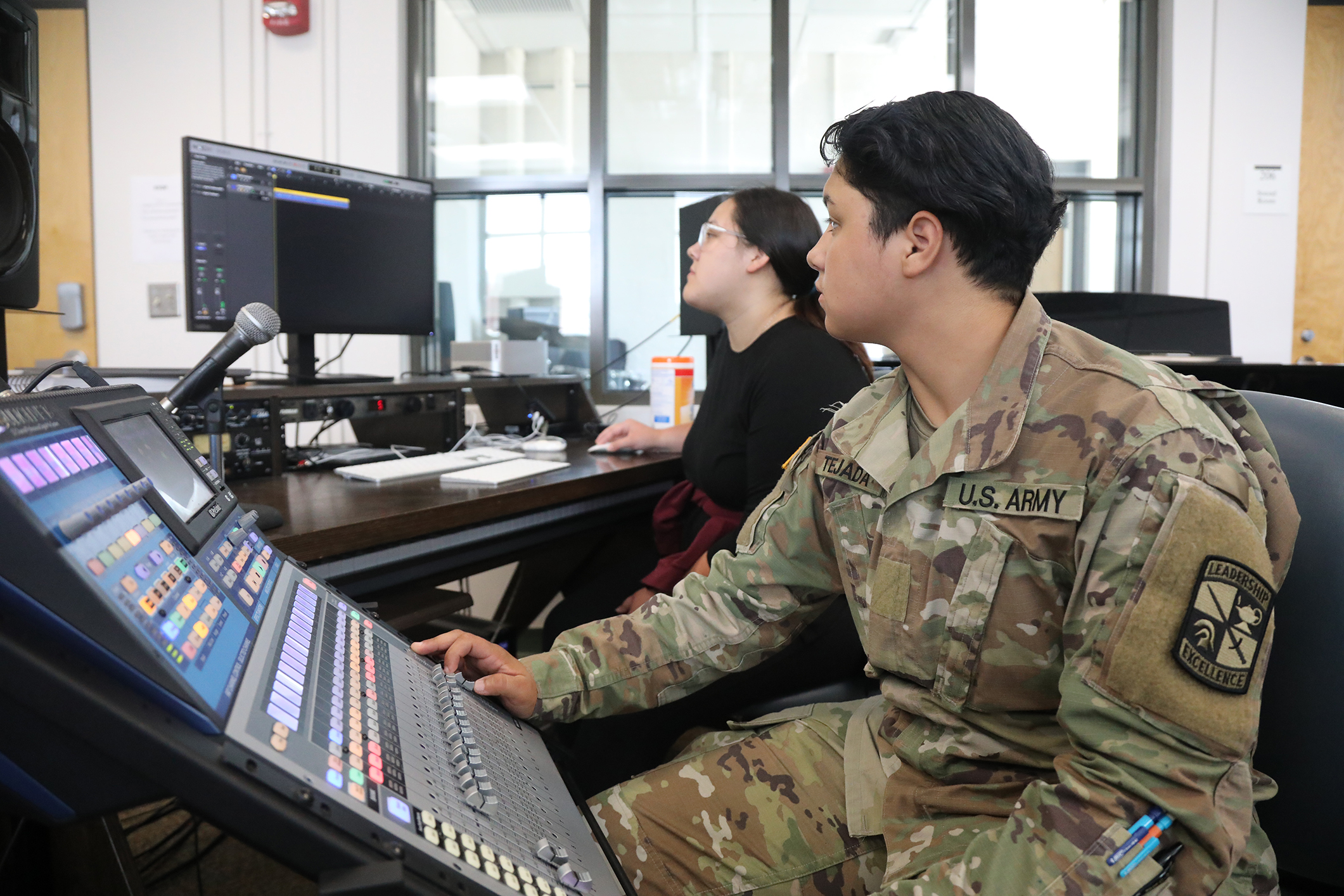 Female at a sound board with another student in the background