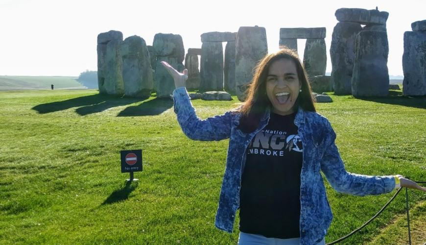 female student laughing at camera posing in front of Stonehenge