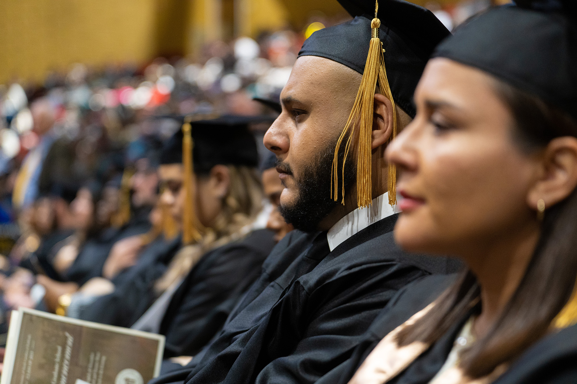 A row of graduates in cap and gown at UNC Pembroke commencement.