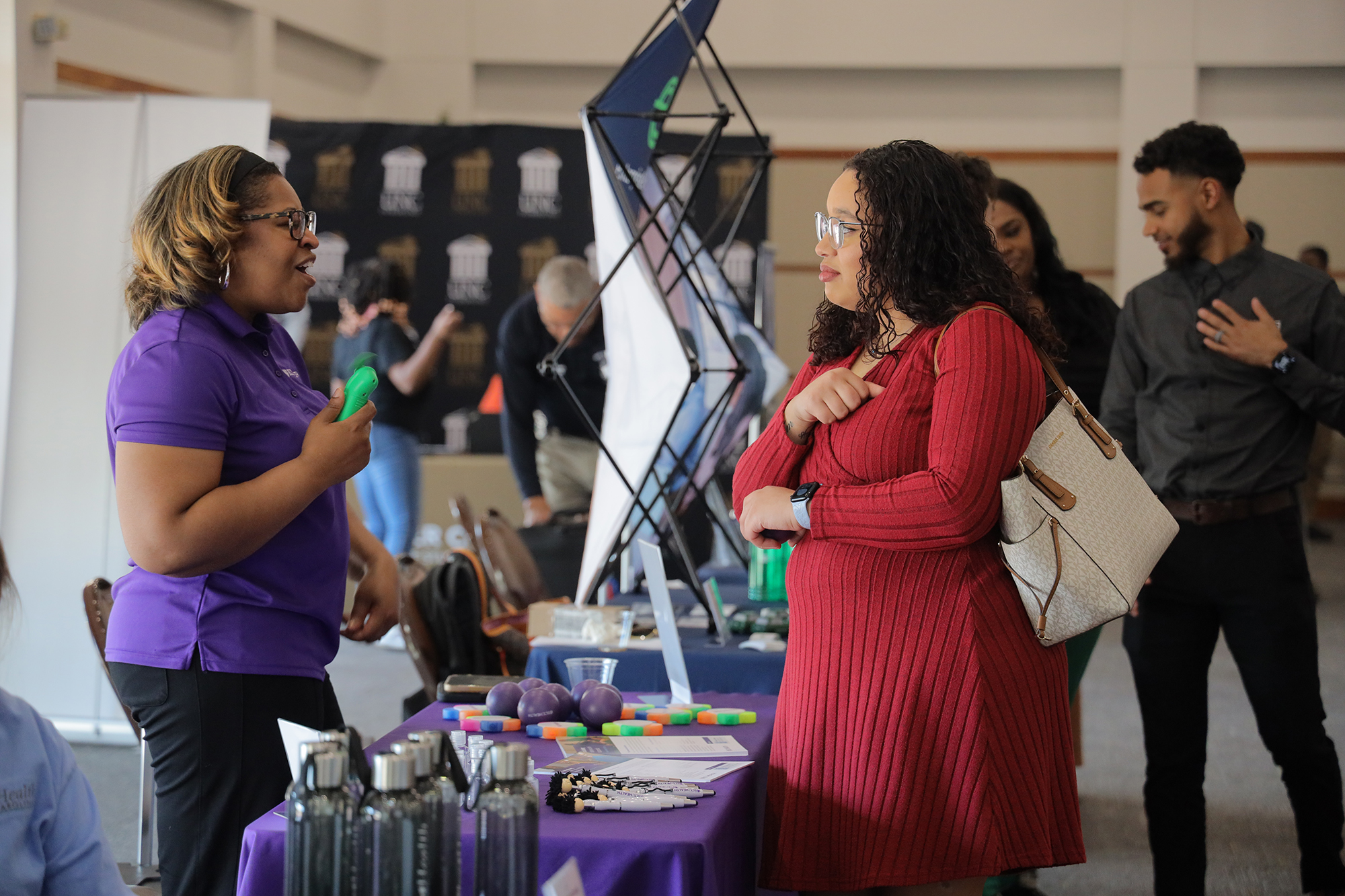 an employer speaks to a female UNCP student at a job fair