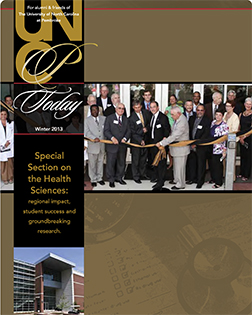 large crowd including the chancellor at a ribbon cutting from the cover of the UNCP Today winter 2013 edition